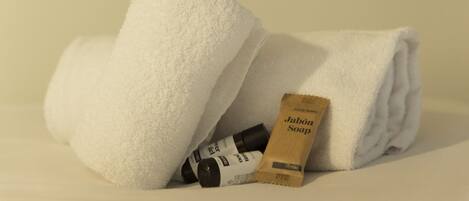 A neatly folded white towel and a bar of soap on a white surface.