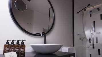 A bathroom with a round mirror, a white sink, and a shower.