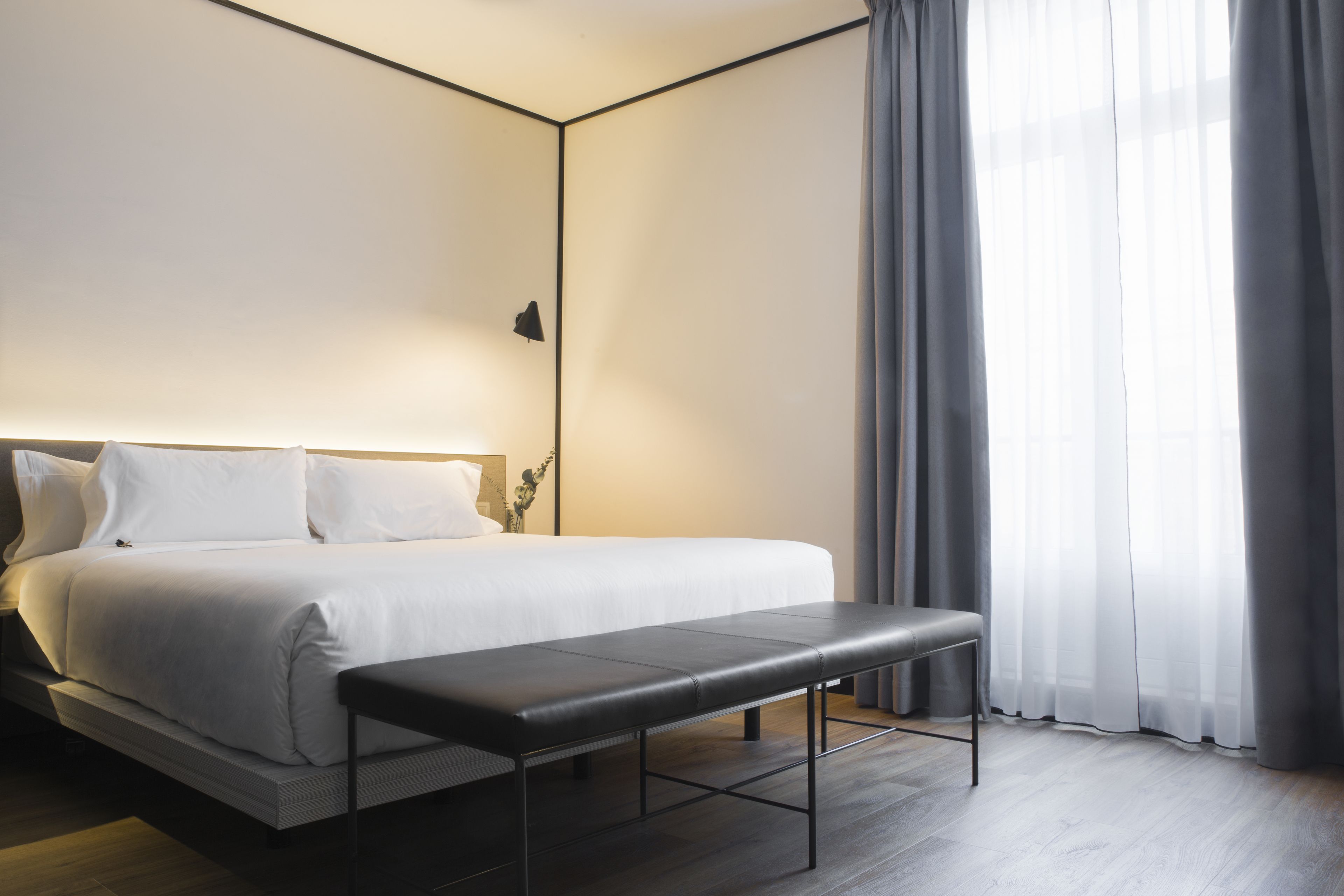 Un dormitorio moderno con una cama grande, un banco y una mesita de noche.
