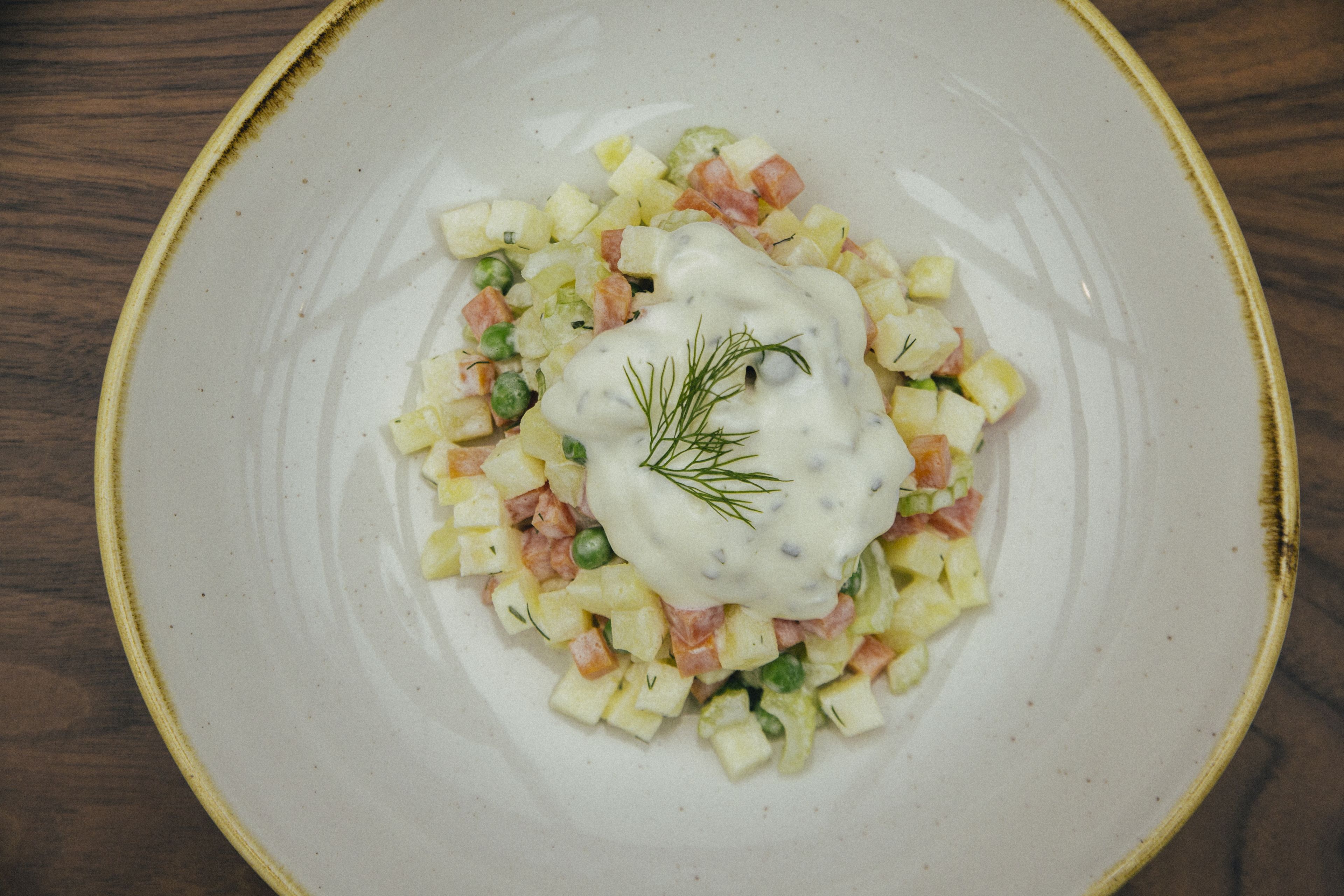 A plate of potato salad with a creamy dressing and dill garnish.