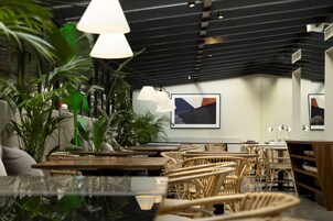 A modern interior with wicker furniture, pendant lighting, and indoor plants.