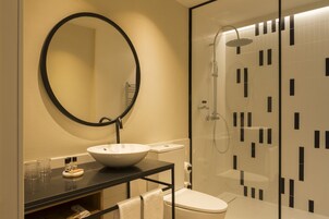 A modern bathroom with a round mirror, a white sink, and a glass-enclosed shower.