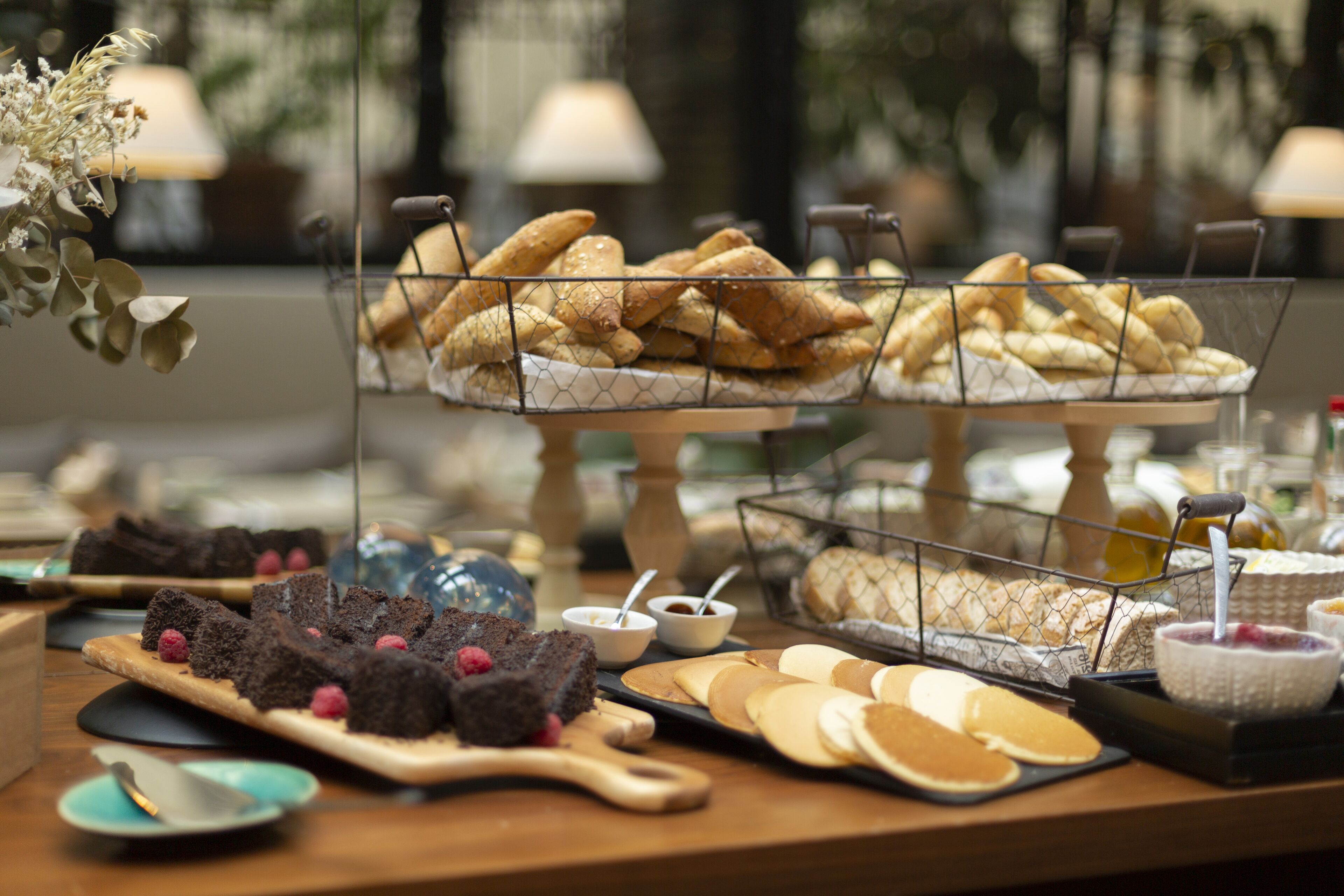 Una mesa de buffet con diversos alimentos, incluyendo pasteles, postres y queso.