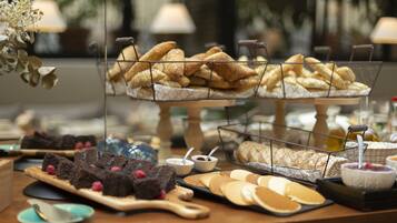 Una mesa de buffet con diversos alimentos, incluyendo pasteles, postres y queso.