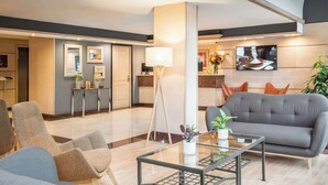 A modern hotel lobby with a seating area, a glass coffee table, and a kitchen visible in the background. - Sunotel Junior (Barcelona)
