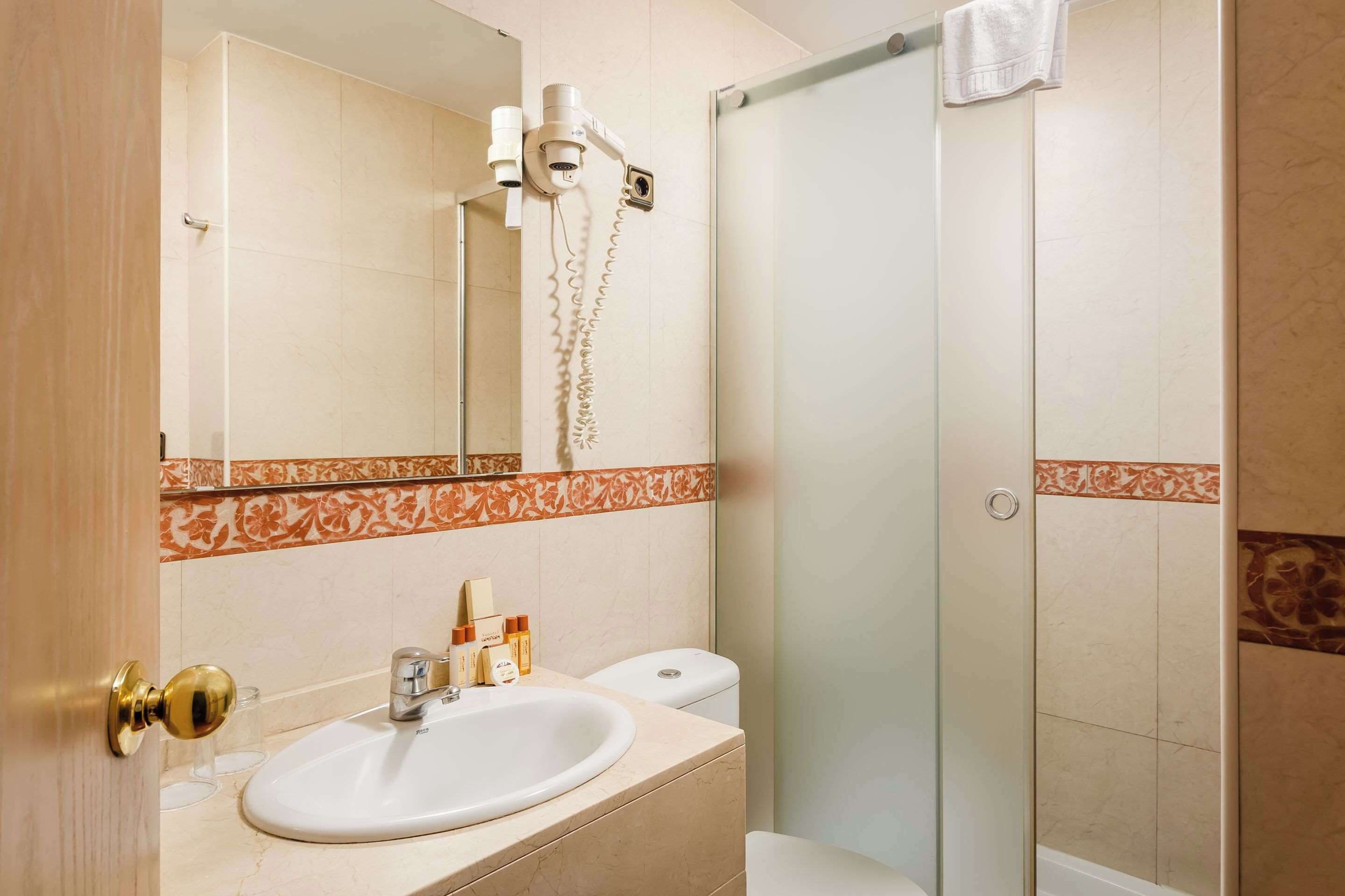 A bathroom with a sink, mirror, and shower.