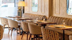 A restaurant with a cozy seating area, tables with chairs, and a lamp. - Sunotel Junior (Barcelona)