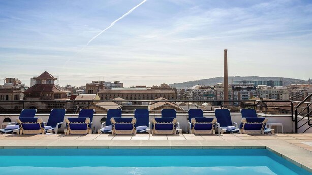 A rooftop pool area with lounge chairs and a view of the cityscape. - Petit Palace Junior formerly known as Sunotel Junior (Barcelona)
