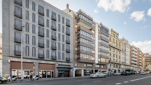 A multi-story building with a row of shops on the ground floor, including a pharmacy and a restaurant. - Petit Palace Junior formerly known as Sunotel Junior (Barcelona)