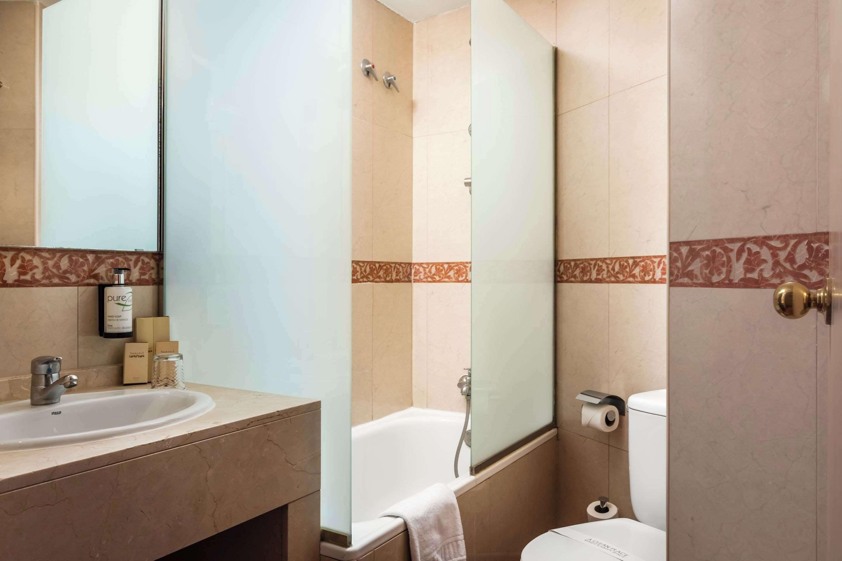 Un baño con lavamanos, espejo, inodoro y bañera.