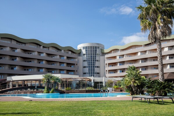 A hotel with a pool, palm trees, and a modern architecture. - MS Aparthotel (Oeiras)