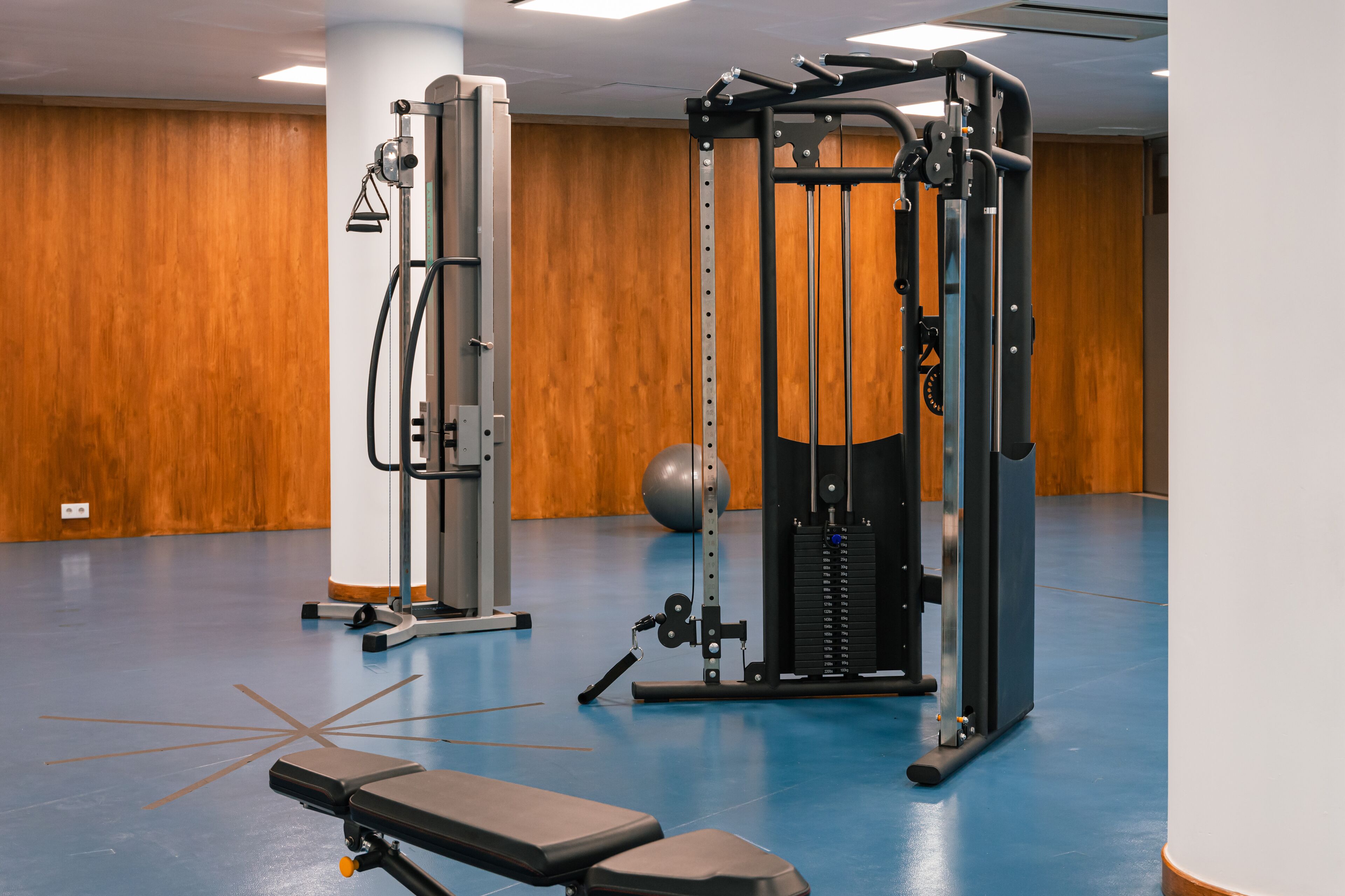 A gym with exercise equipment, a bench, and a ball.