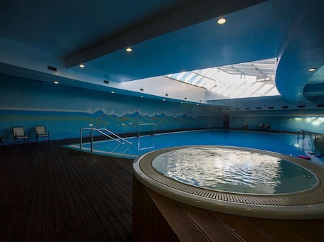 Una piscina techada, una piscina al aire libre, sombrillas