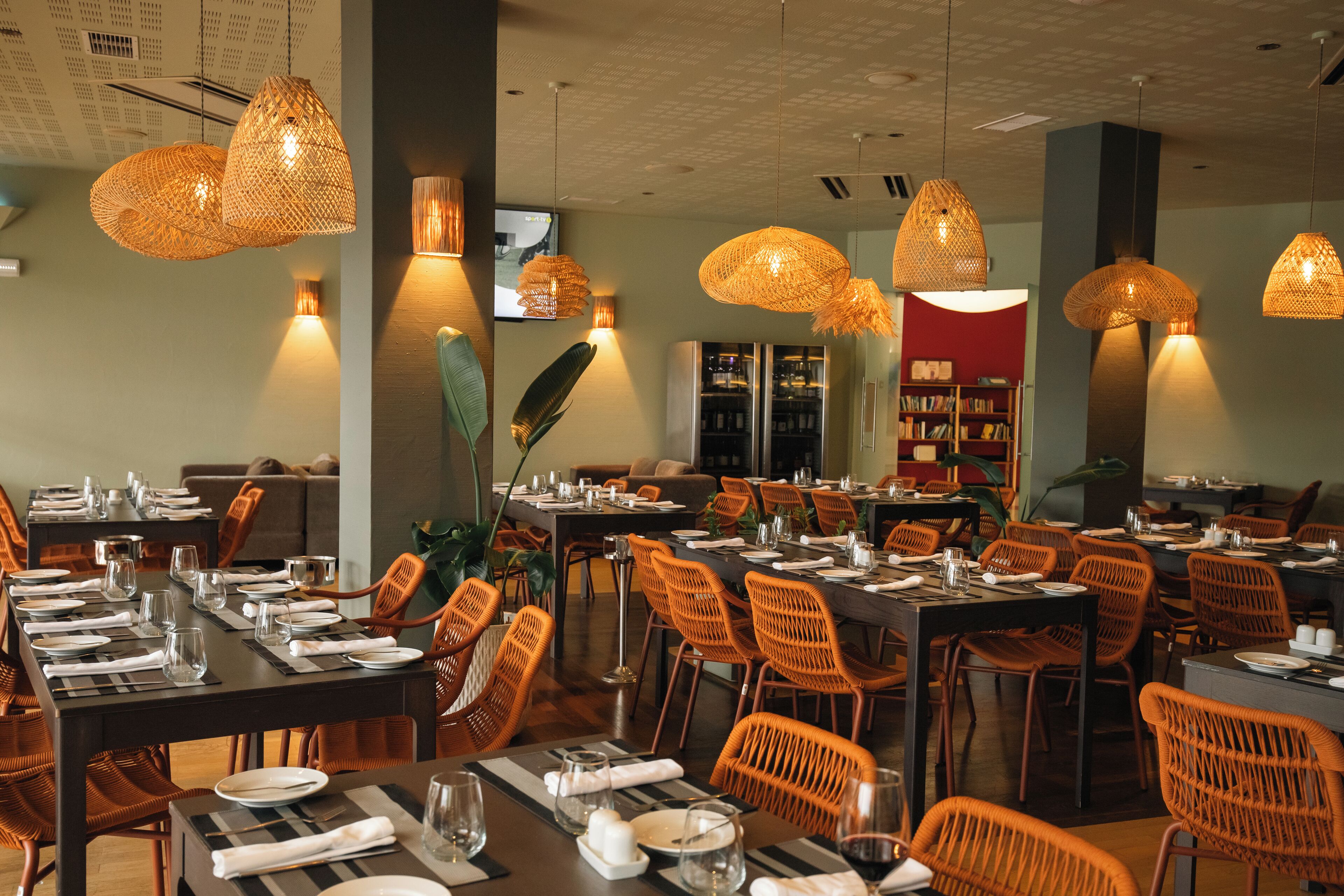 A restaurant with multiple dining tables set with plates, glasses, and cutlery.