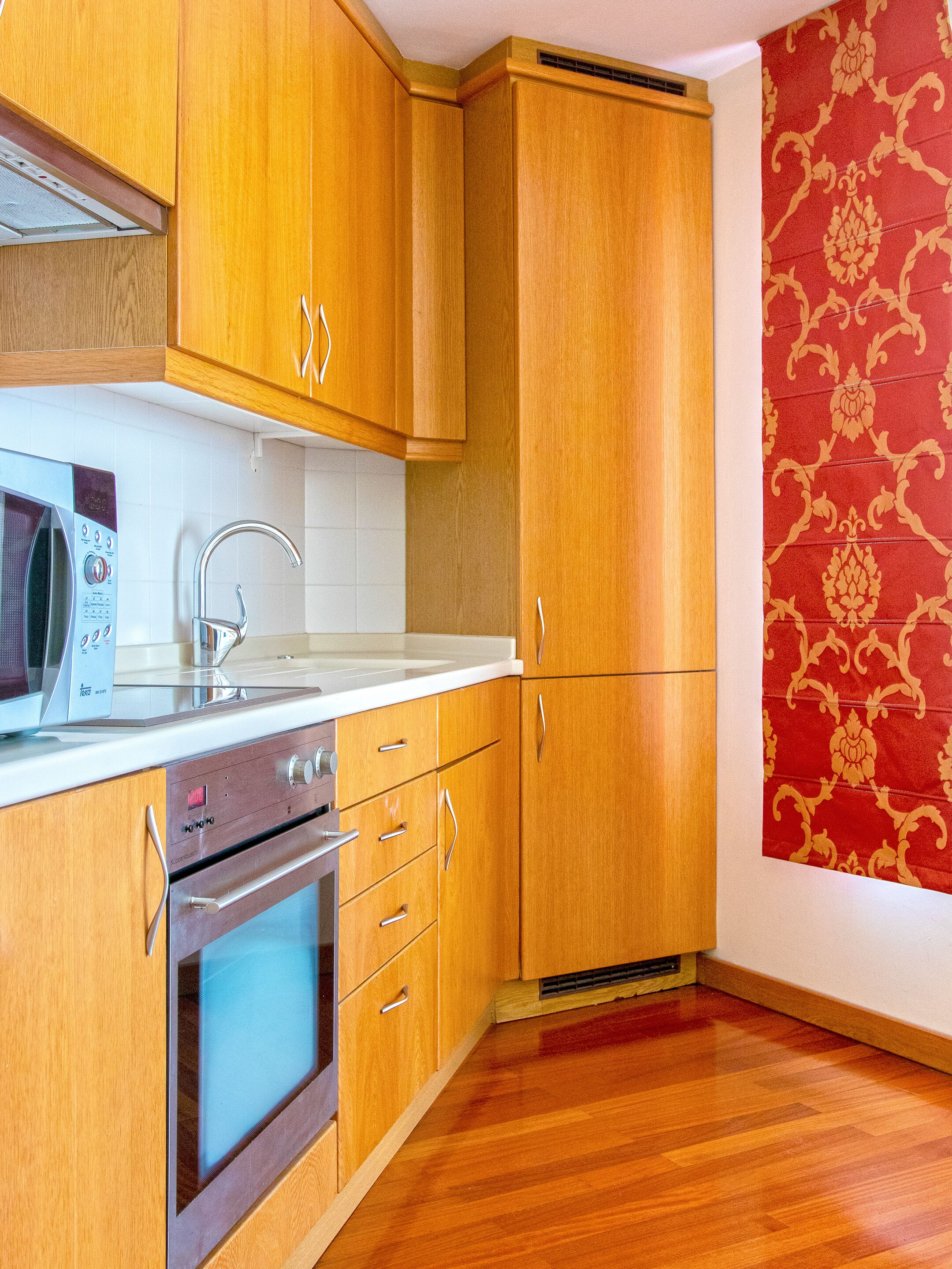 A kitchen with wooden cabinets, a microwave, a sink, and an oven.