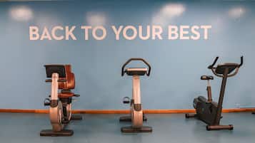 Three stationary bikes in a room with a blue wall and the text "BACK TO YOUR BEST".