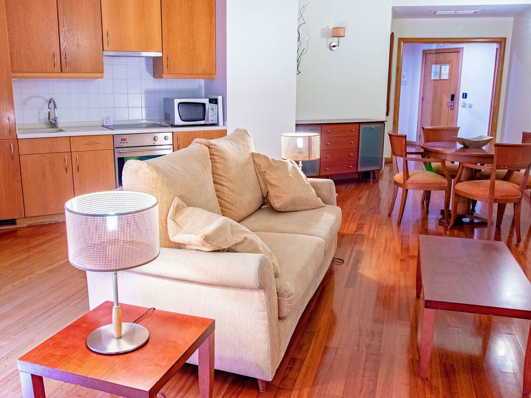 A living room with a sofa, a coffee table, and a dining area with chairs and a table.