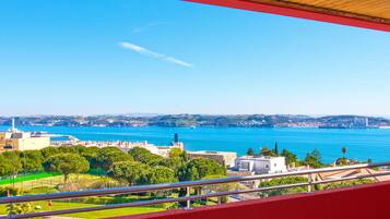 Uma varanda com vista para um horizonte costeiro, incluindo uma ponte e uma vasta extensão de água.