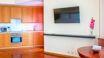 Una cocina moderna con armarios de madera, microondas, horno y televisor de pantalla plana montado en la pared.