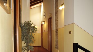 Un pasillo con una planta en maceta, puertas de madera y una escalera con barandilla negra.