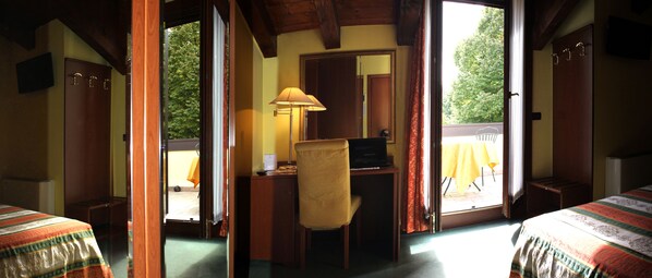 A room with a bed, a desk with a chair, a lamp, and a view of the outdoors through a door. - Hotel Antico Moro (Mestre)