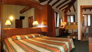 Ein Hotelzimmer mit einem großen Bett, einem Schreibtisch mit Lampe, einem Spiegel und einer Treppe, die in ein weiteres Zimmer führt.