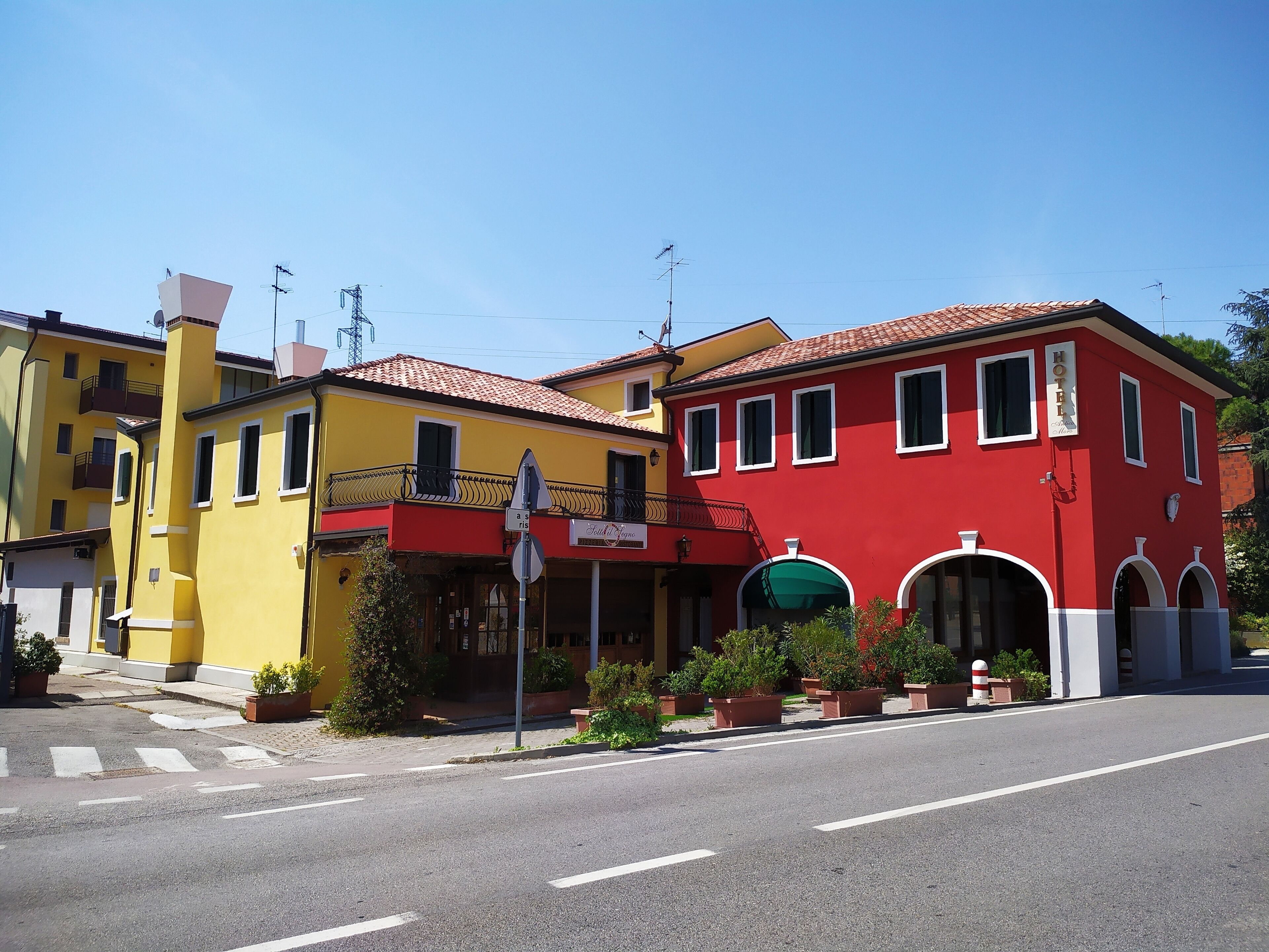 A hotel with a red facade, yellow building adjacent, and a clear sky.
