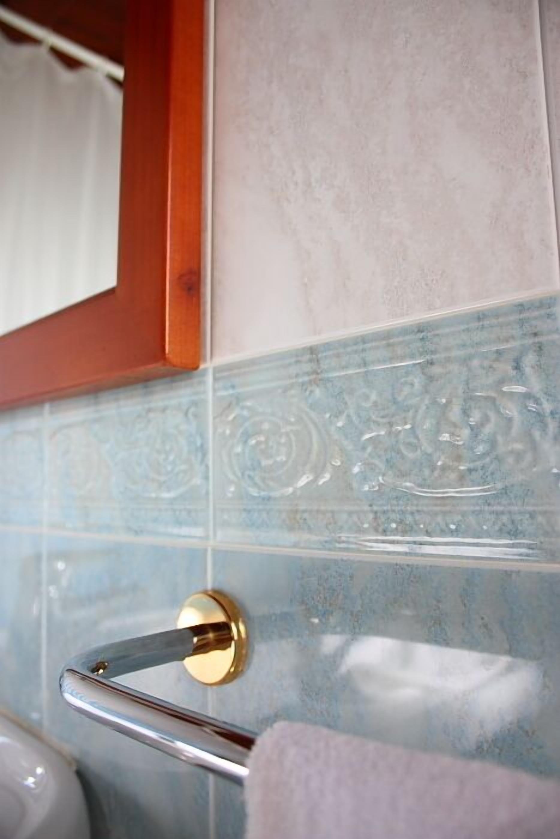 A bathroom with a towel rack, a mirror, and a tiled wall.