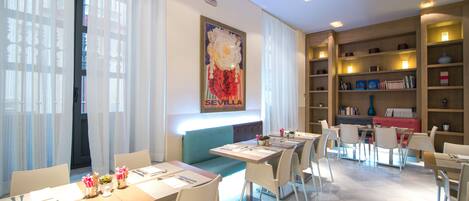 Un comedor moderno con mesas, sillas y una estantería.