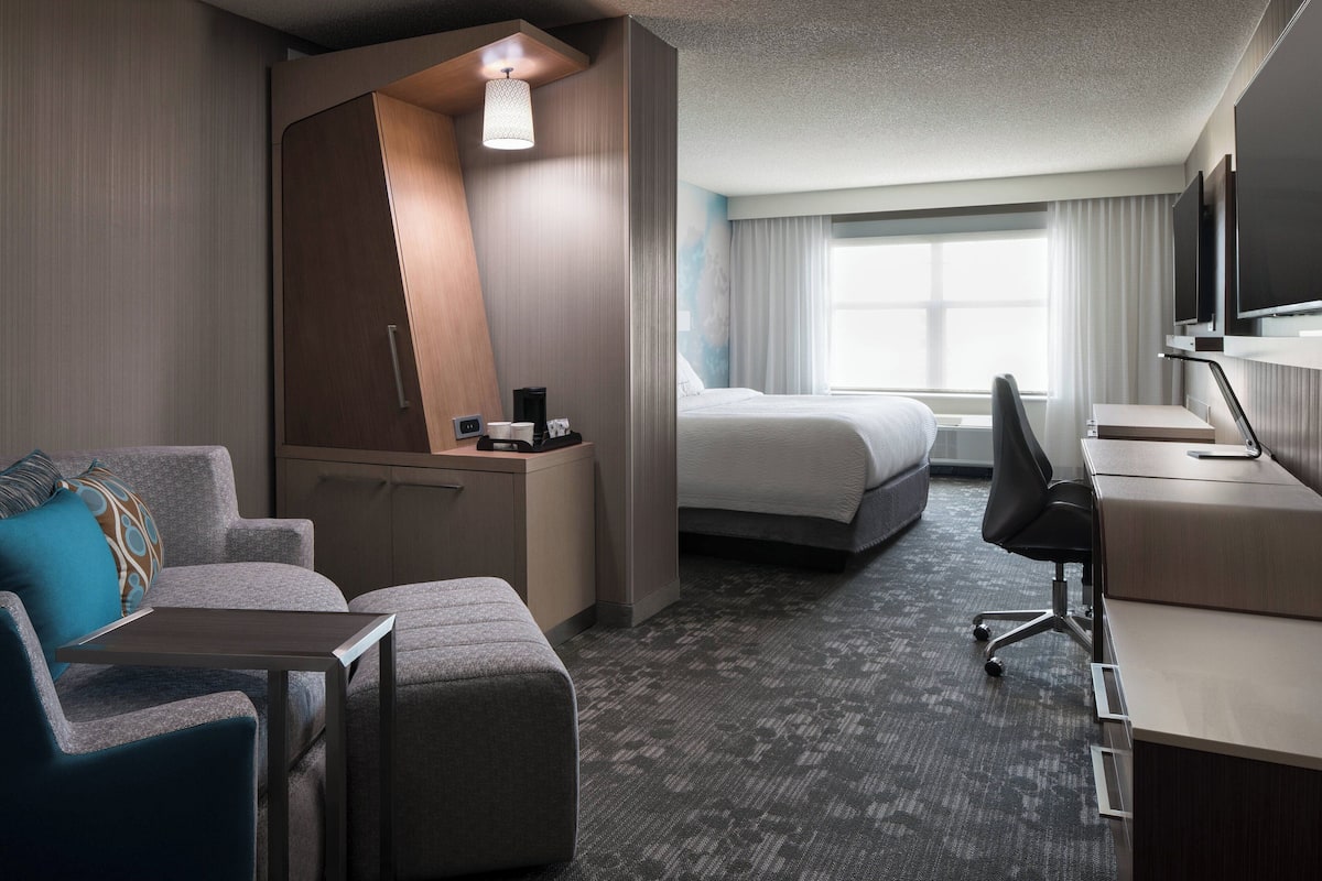 Une chambre d’hôtel équipée d’un lit, d’un bureau, d’une chaise, d’un canapé et d’une télévision.