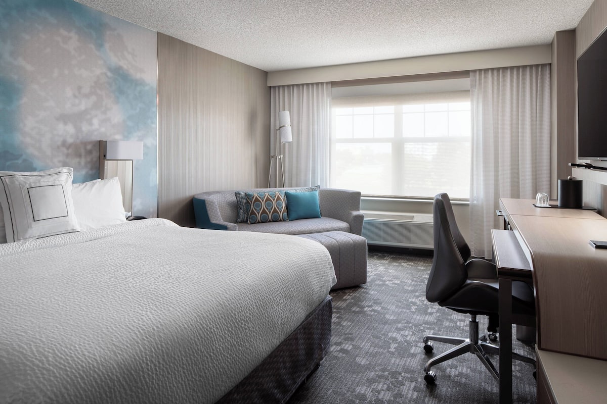 Une chambre d’hôtel avec un grand lit, un canapé, un bureau et une chaise.