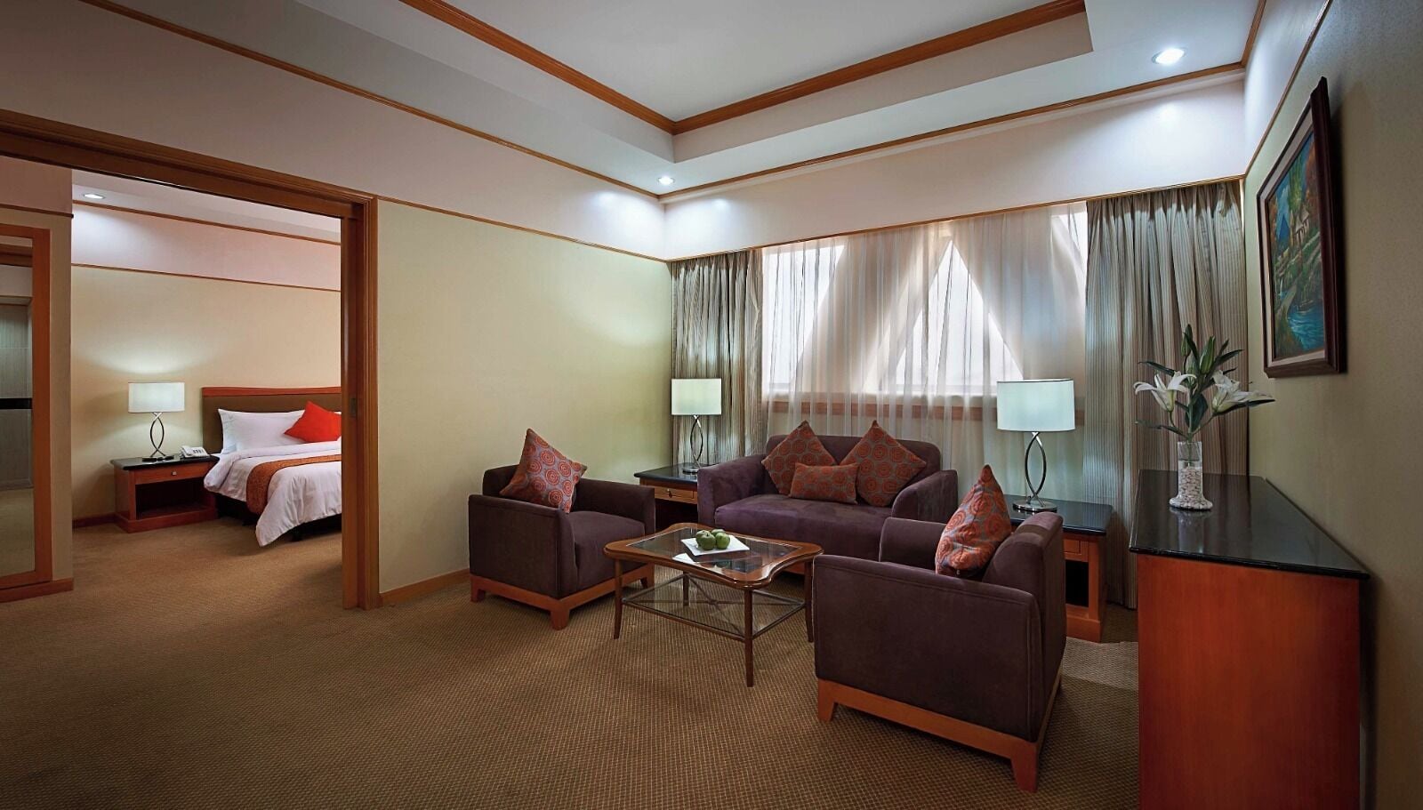 A hotel room with a bed, two sofas, a coffee table, a desk, and a lamp.