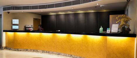 A hotel reception area with a curved counter, a digital screen, and a decorative floor design.