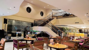 Un interior moderno con una escalera central, varias zonas de estar y un escenario para presentaciones.