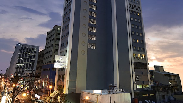 Un edificio alto y moderno con un diseño vertical llamativo, varios pisos y una combinación de paneles de vidrio y sólidos.