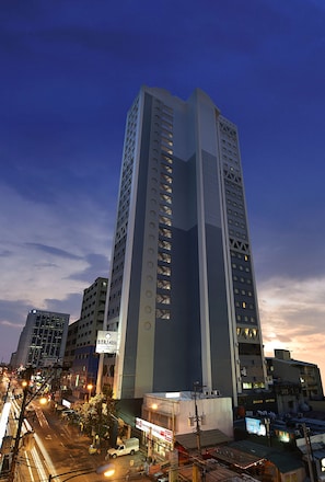 A tall, modern building with a prominent vertical design, multiple floors, and a mix of glass and solid panels. - Berjaya Makati Hotel (Makati)