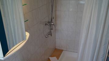 Une salle de bain équipée d’un lavabo, d’un miroir, d’une douche et d’un porte-serviettes.