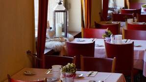 A dining area with tables set for four, red chairs, and a candle centerpiece. - Hotel Victoria (Brig)