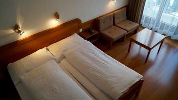 Ein Hotelzimmer mit einem Holzbett, einer Couch, einem kleinen Tisch und Blick aus einem Fenster.