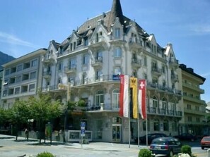Un hotel de varios pisos con un estilo arquitectónico clásico, que cuenta con balcones y una torre prominente en una esquina.
