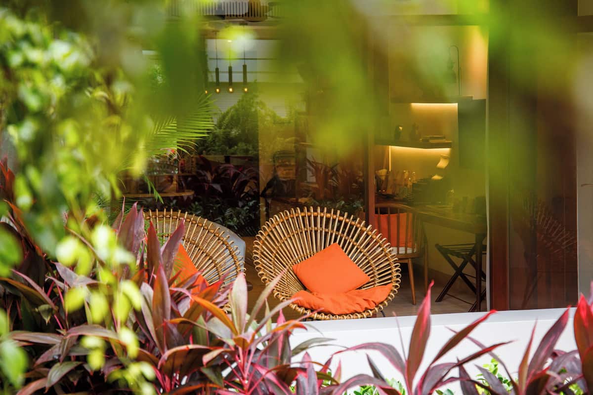 A room with wicker chairs, a table, and a glass partition.