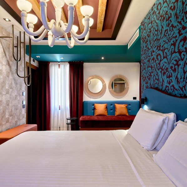 A hotel room with a large bed, a blue headboard, a red sofa, and a chandelier. - Ca D Oro (Venice)