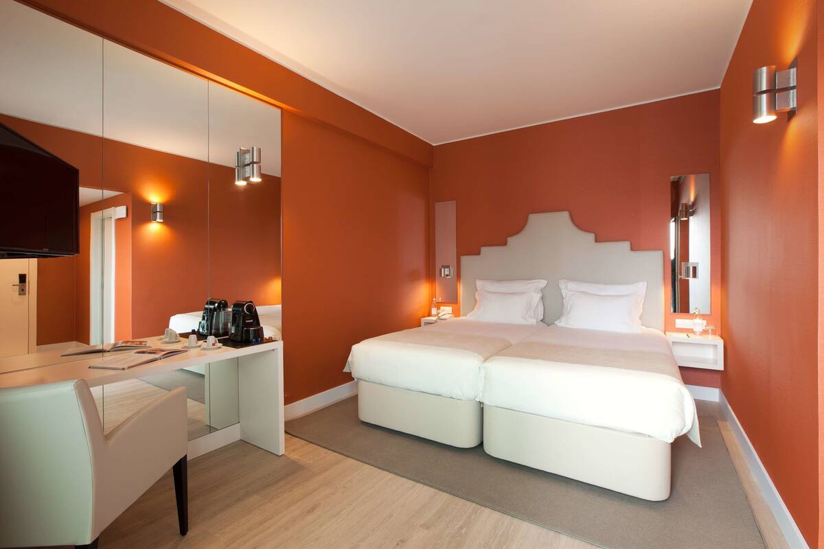 A modern hotel room with a large bed, a desk, and a television.