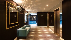 Un moderno vestíbulo de hotel con piso de diseño geométrico, un sofá azul claro y una bola de discoteca.
