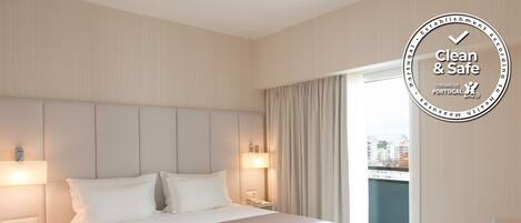 Ein sauberes und sicheres Hotelzimmer mit einem Bett, Nachttischen und Blick auf die Stadt durch das Fenster.