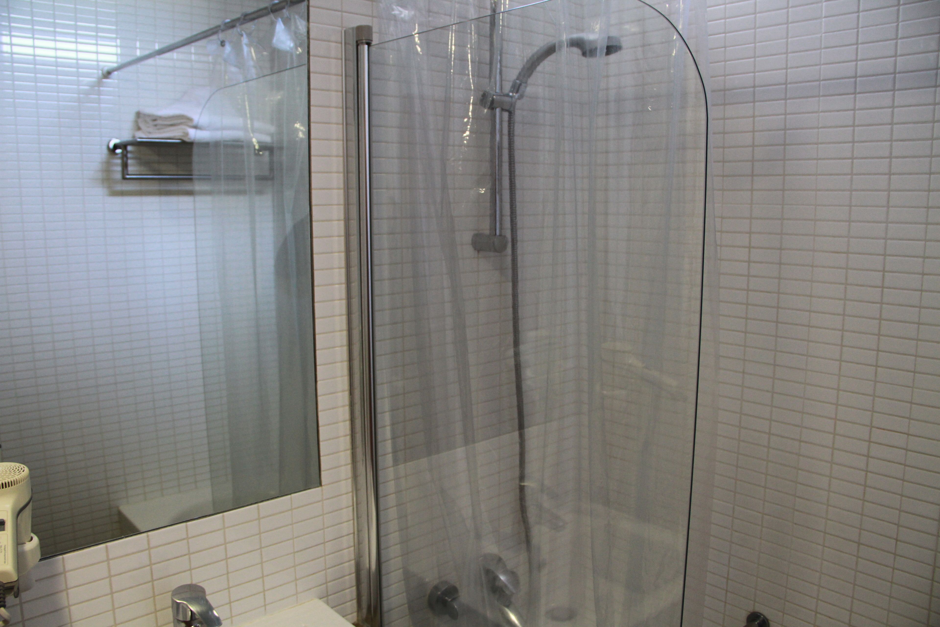 Une cabine de douche fermée par des parois en verre, dotée d’un pommeau de douche à main, d’un porte-serviettes et d’un miroir.
