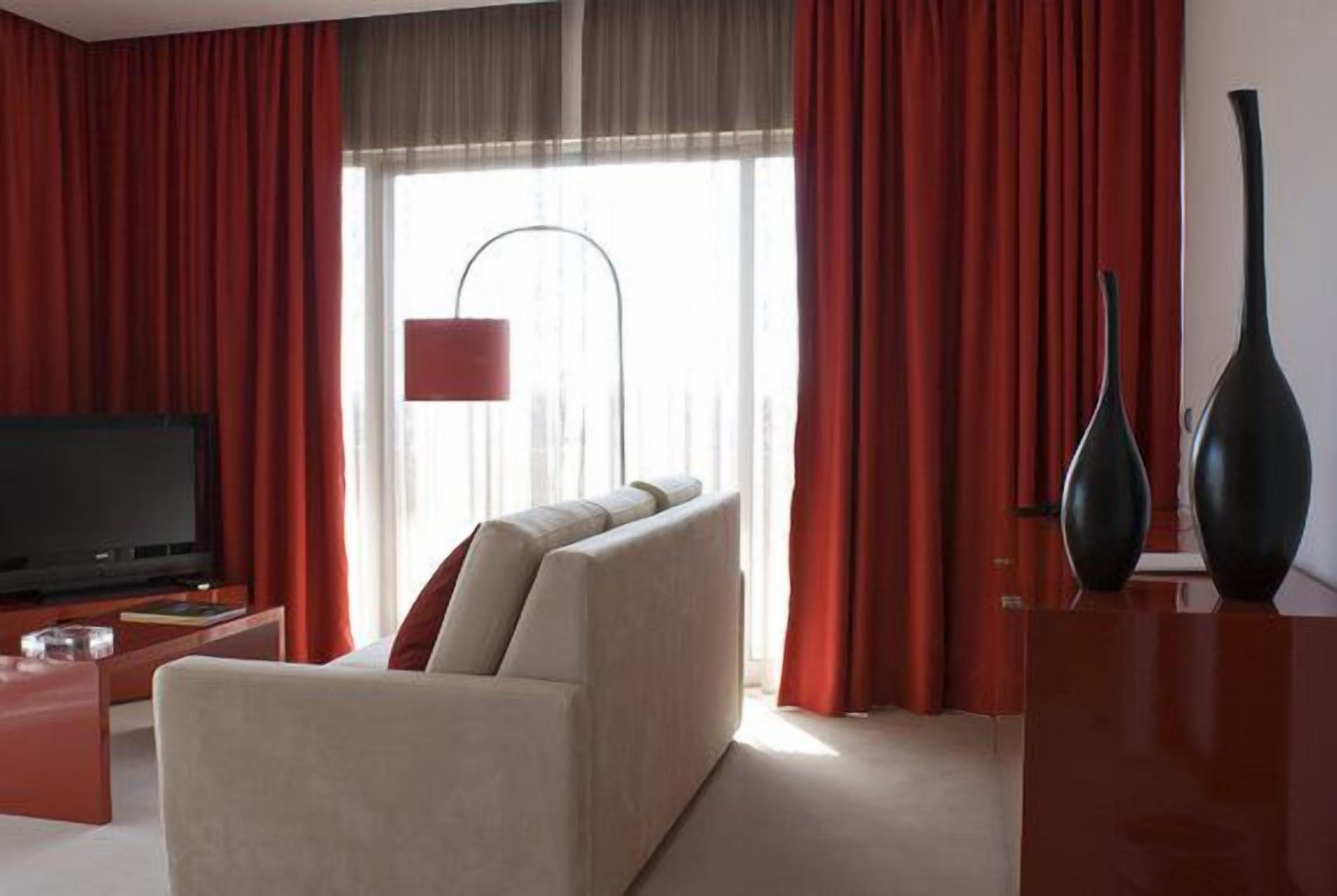 Un salon moderne avec un canapé, un téléviseur et un rideau rouge.