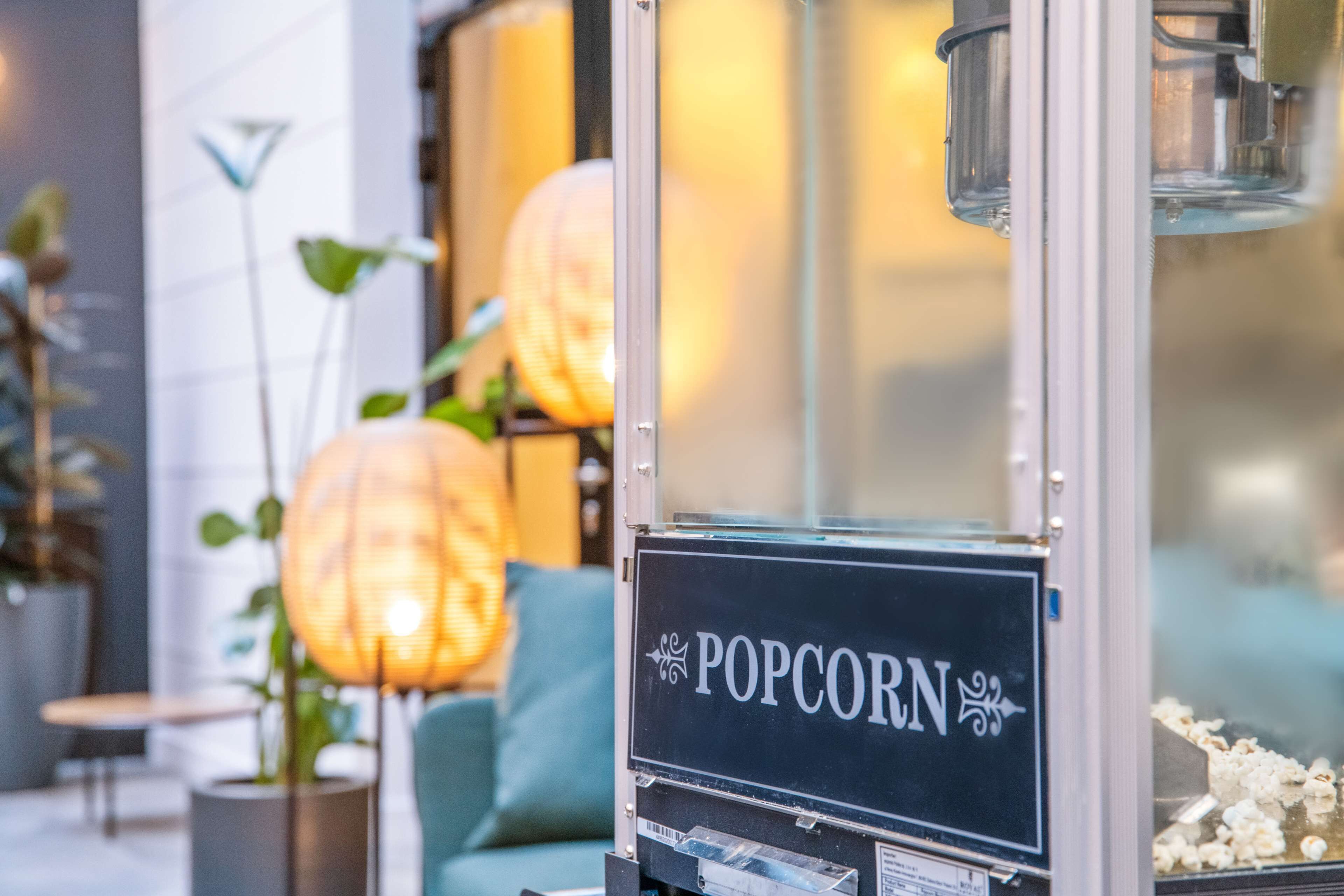 En popcornmaskine med et skilt, der viser ordet "POPCORN" i et moderne indendørs miljø.