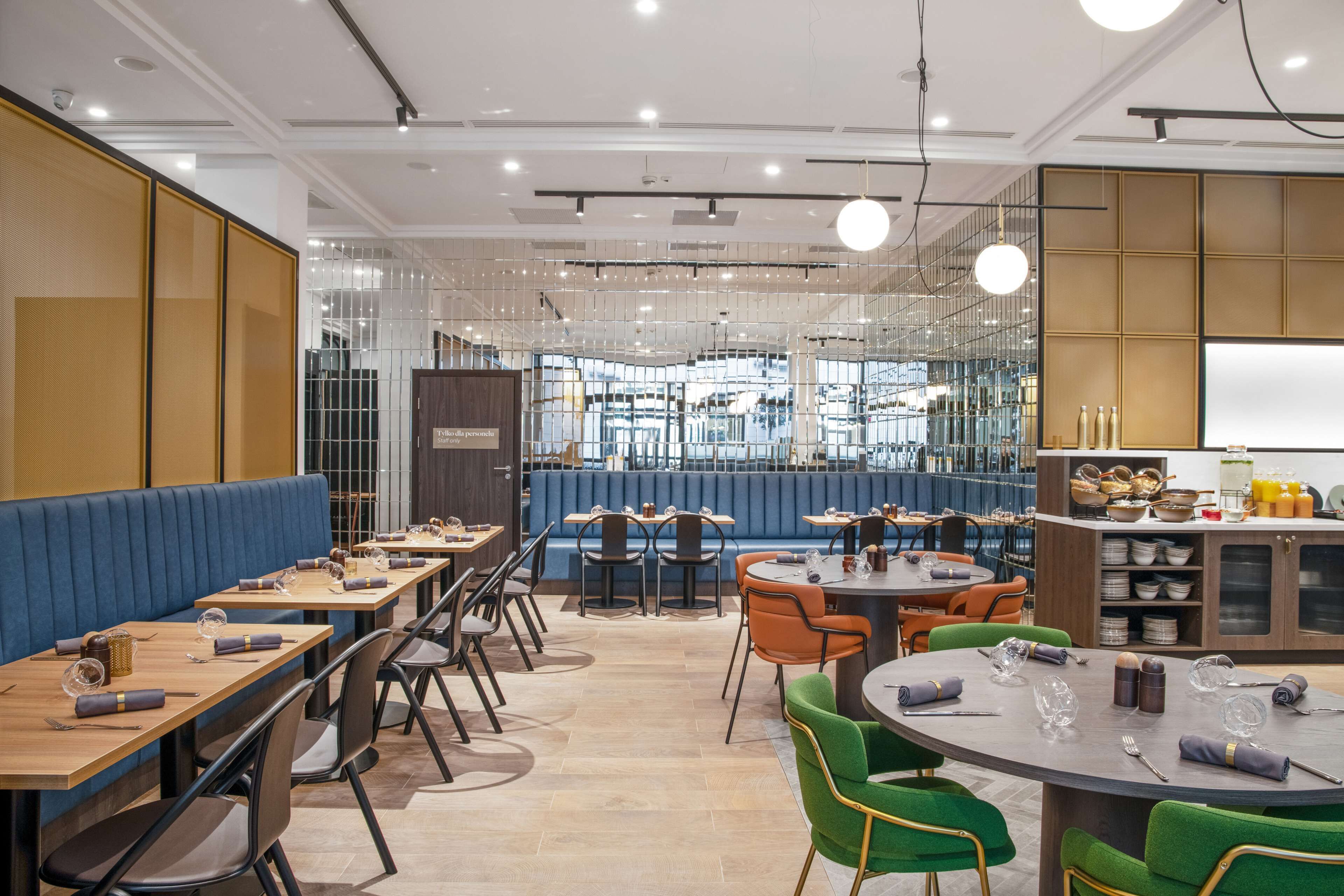 Een modern restaurant met zitbankjes en tafels, een bar en een uitzicht op de stad door grote ramen.