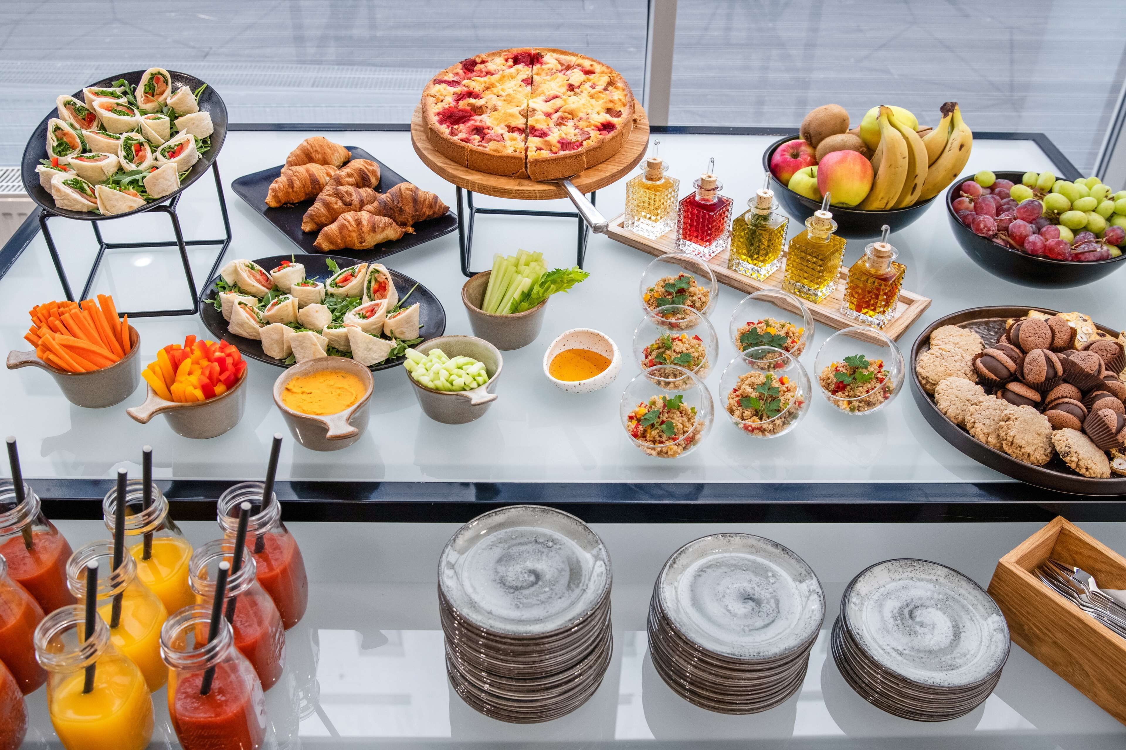 A buffet table with various food items including sandwiches, salads, fruits, and beverages.